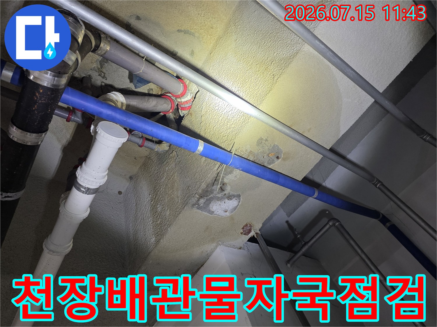 콘크리트-천장에-설치된-다양한-색상의-배관들과-누수로-인한-노란색-얼룩