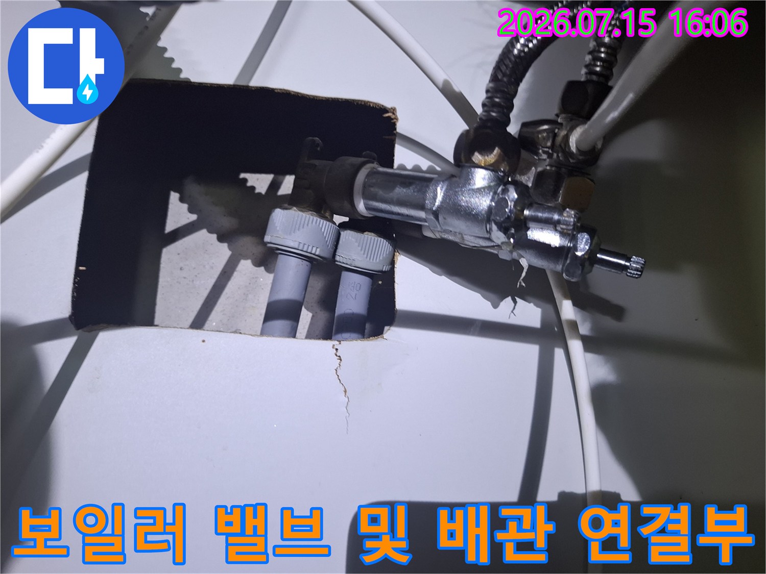 두 개의 회색 배관이 은색 금속 밸브 뭉치에 고정되어 있는 모습