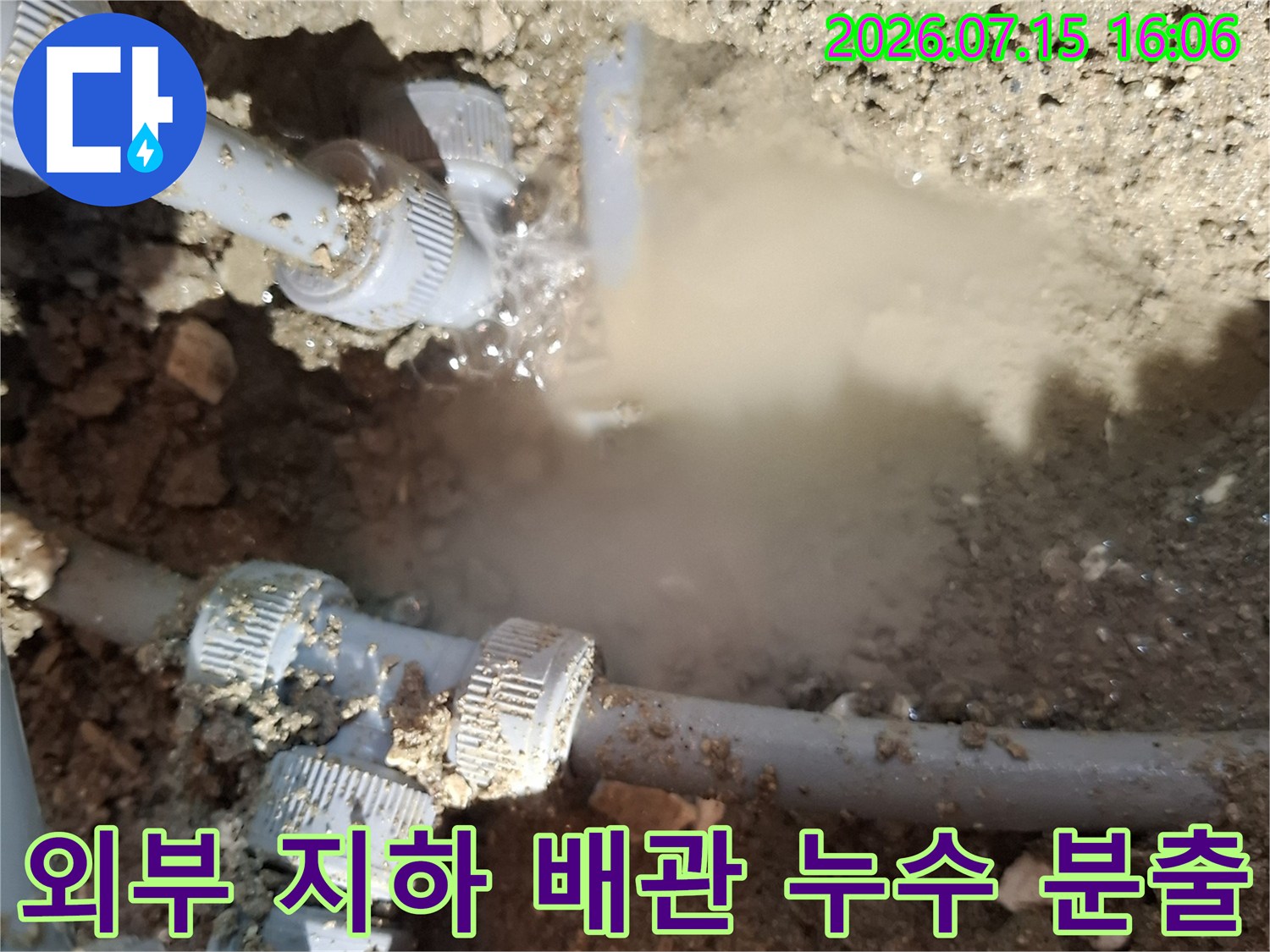흙 속에 묻혀 있던 수도 배관의 결합 부분에서 물이 세차게 뿜어져 나오는 모습