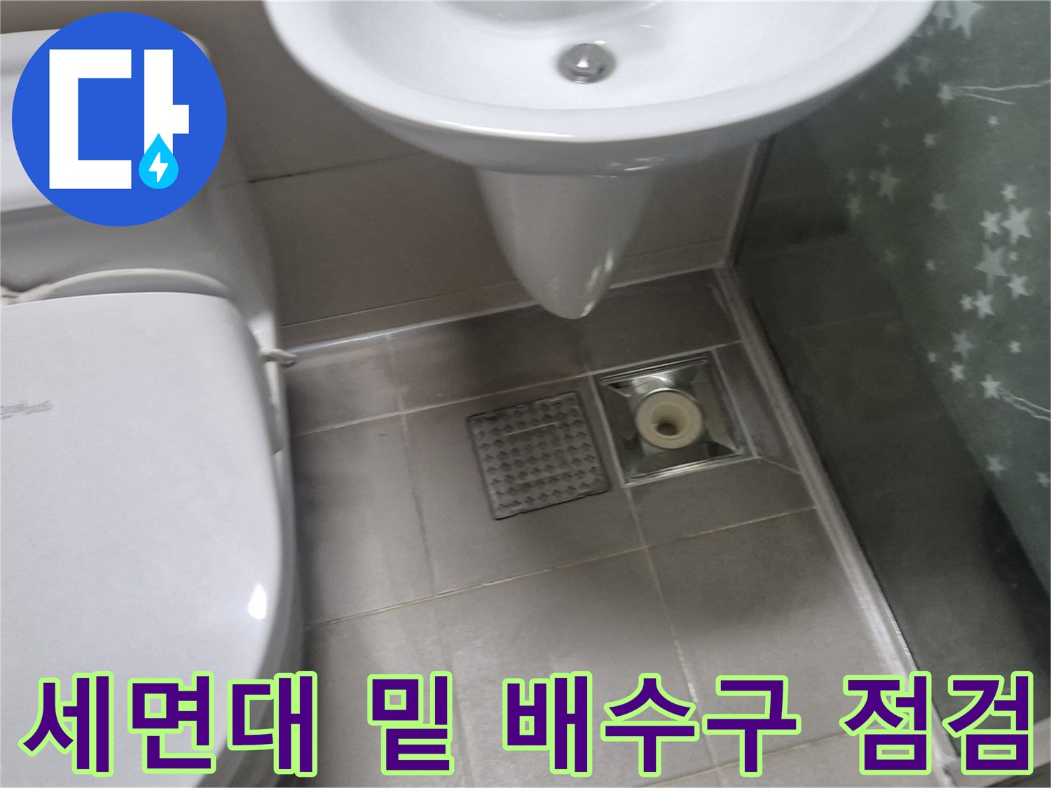 세면대 하단과 변기 근처의 바닥 배수구와 타일 마감 모습입니다.