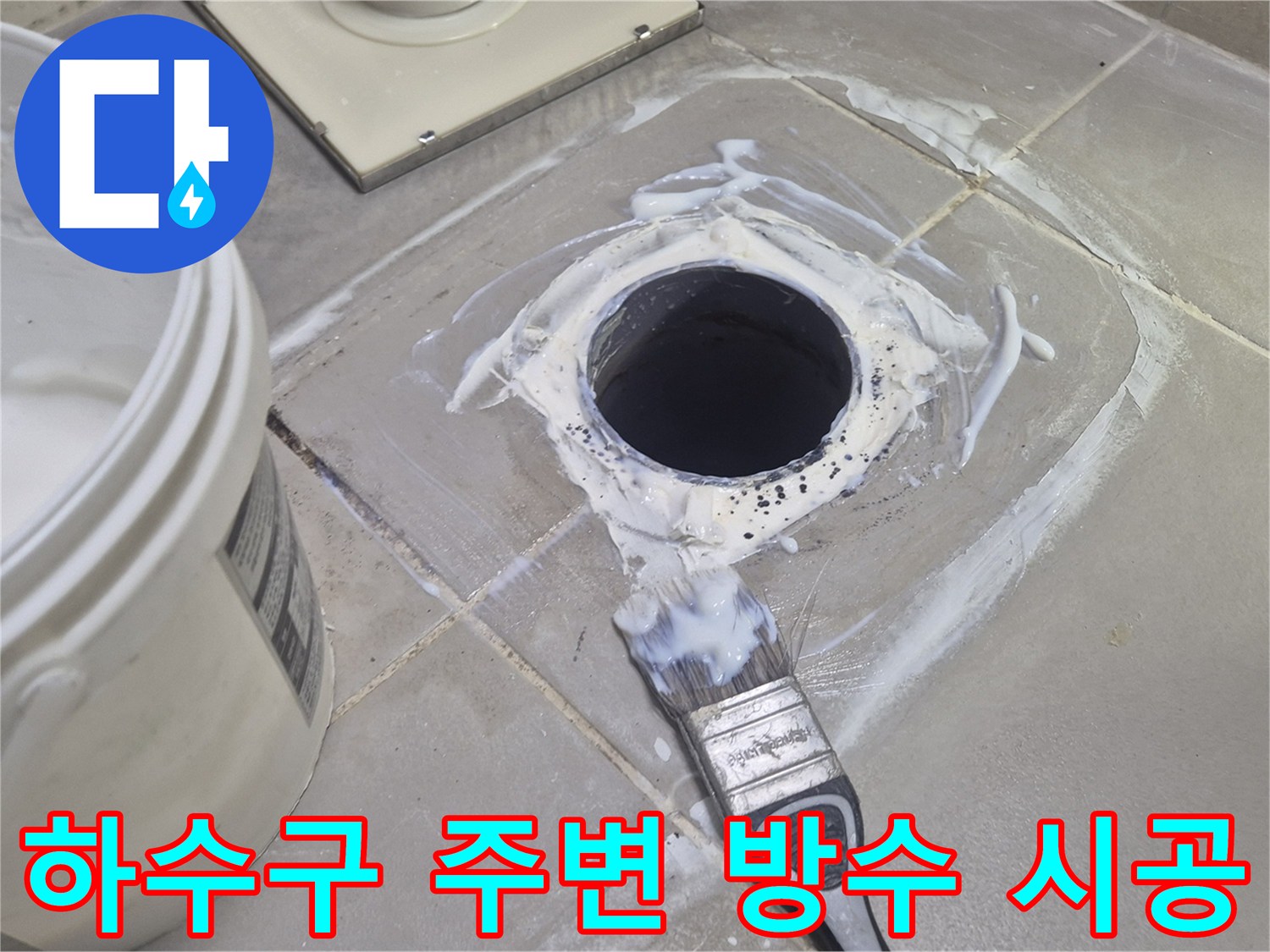 흰색 방수재가 발라진 배수구와 작업용 붓의 모습