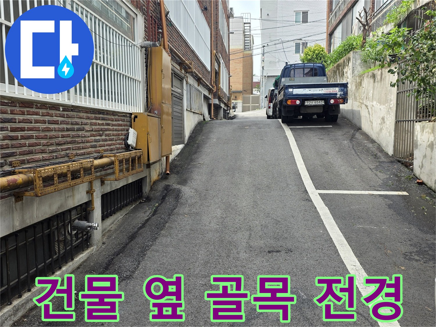 건물 외벽과 아스팔트 도로가 인접한 현장 모습입니다.
