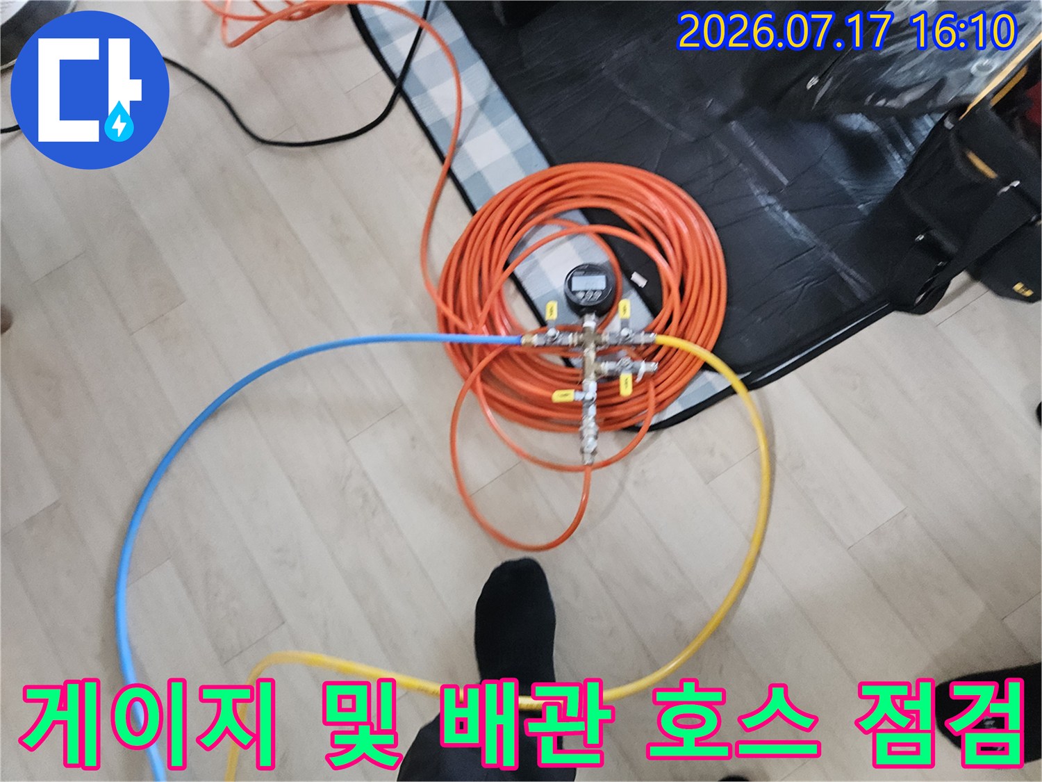 오렌지색의 긴 호스와 게이지가 연결된 정밀 누수 진단 장치
