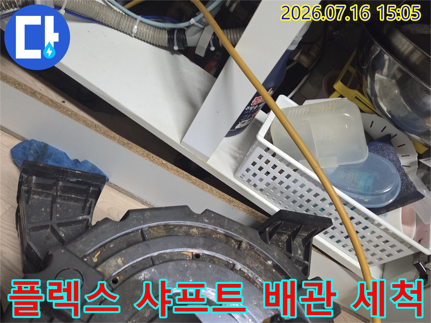회전하는 샤프트 장비를 이용해 싱크대 하부 배관 내의 끈적한 슬러지를 제거하는 장면입니다.