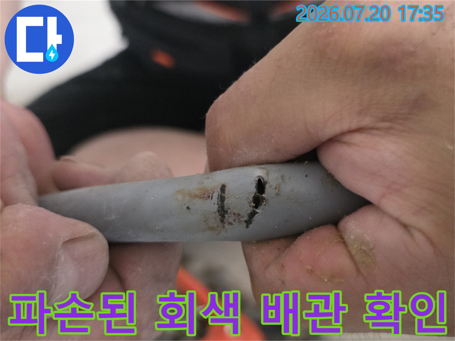 손으로 잡고 있는 파손된 회색 PE 배관의 누수 부위