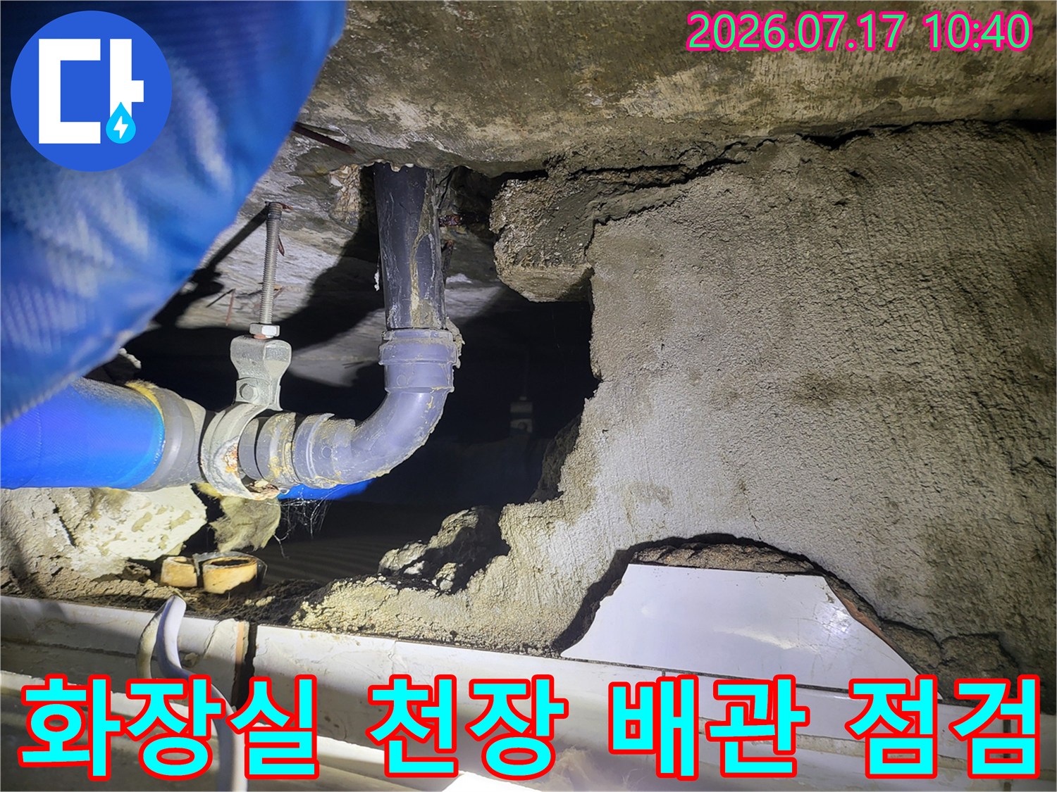 천장 내부에 노출된 배관과 파란색 호스를 연결하여 압력을 체크하는 현장 모습