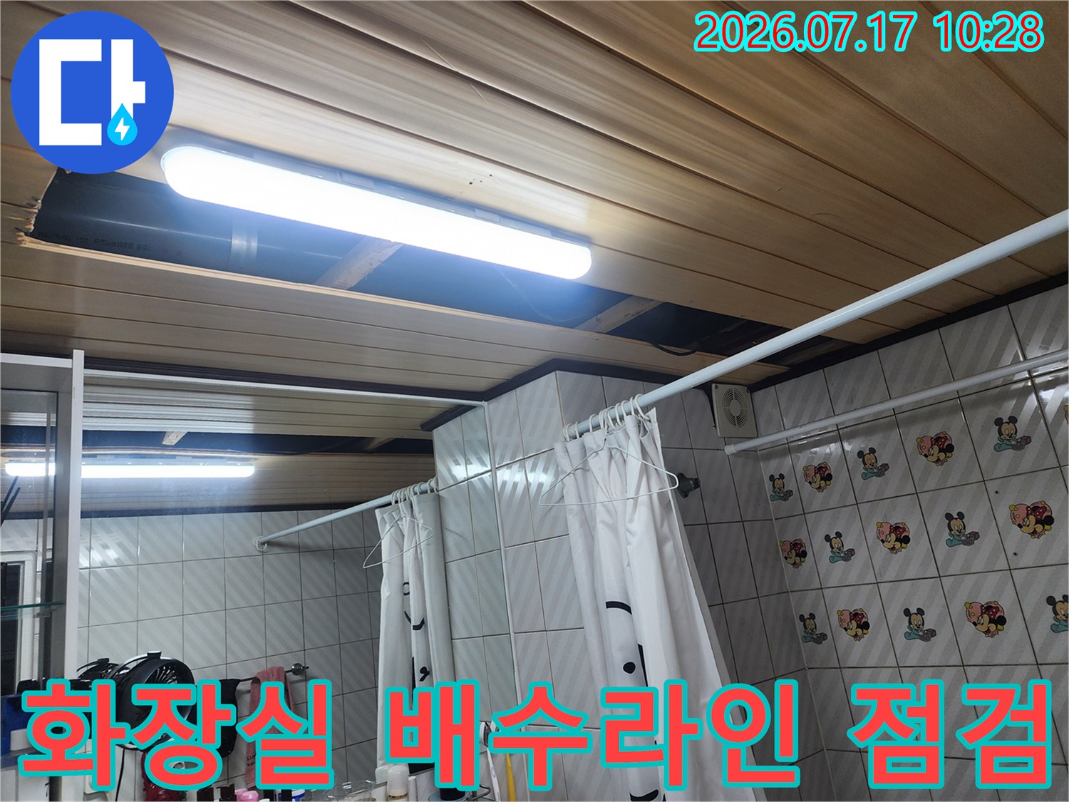 세면대 하단 배수 호스 연결 부위를 점검하는 화장실 내부 모습