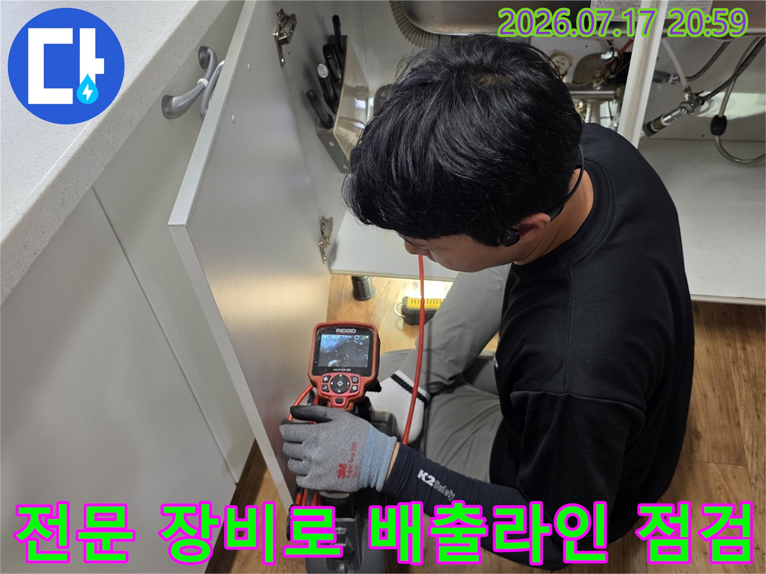 싱크대 아래 공간에서 전문 탐지기를 활용해 누수 지점을 찾아내는 기술적인 작업 과정