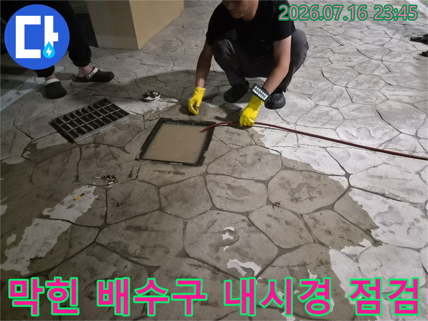 작업자가 노란 장갑을 끼고 배관 내부를 살피기 위해 카메라를 조절하는 모습