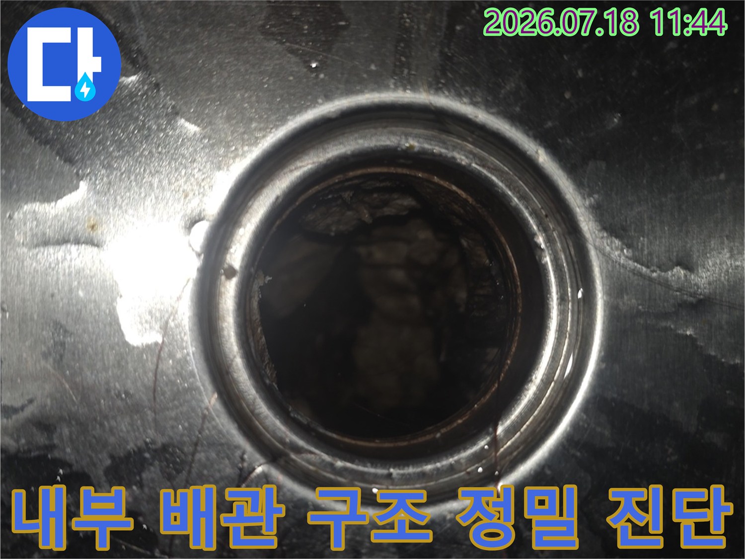 금속 프레임으로 감싸진 점검구를 통해 내부 누수 경로를 파악하는 장면