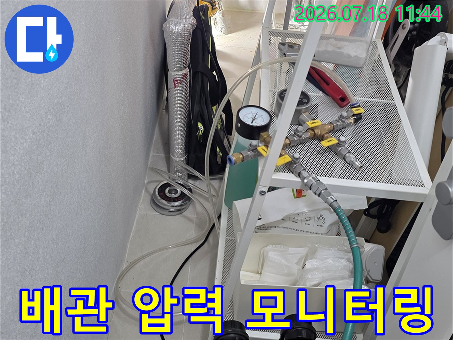 천장 배관에 공압 장비를 연결하여 기밀 상태를 정밀하게 점검하는 장면
