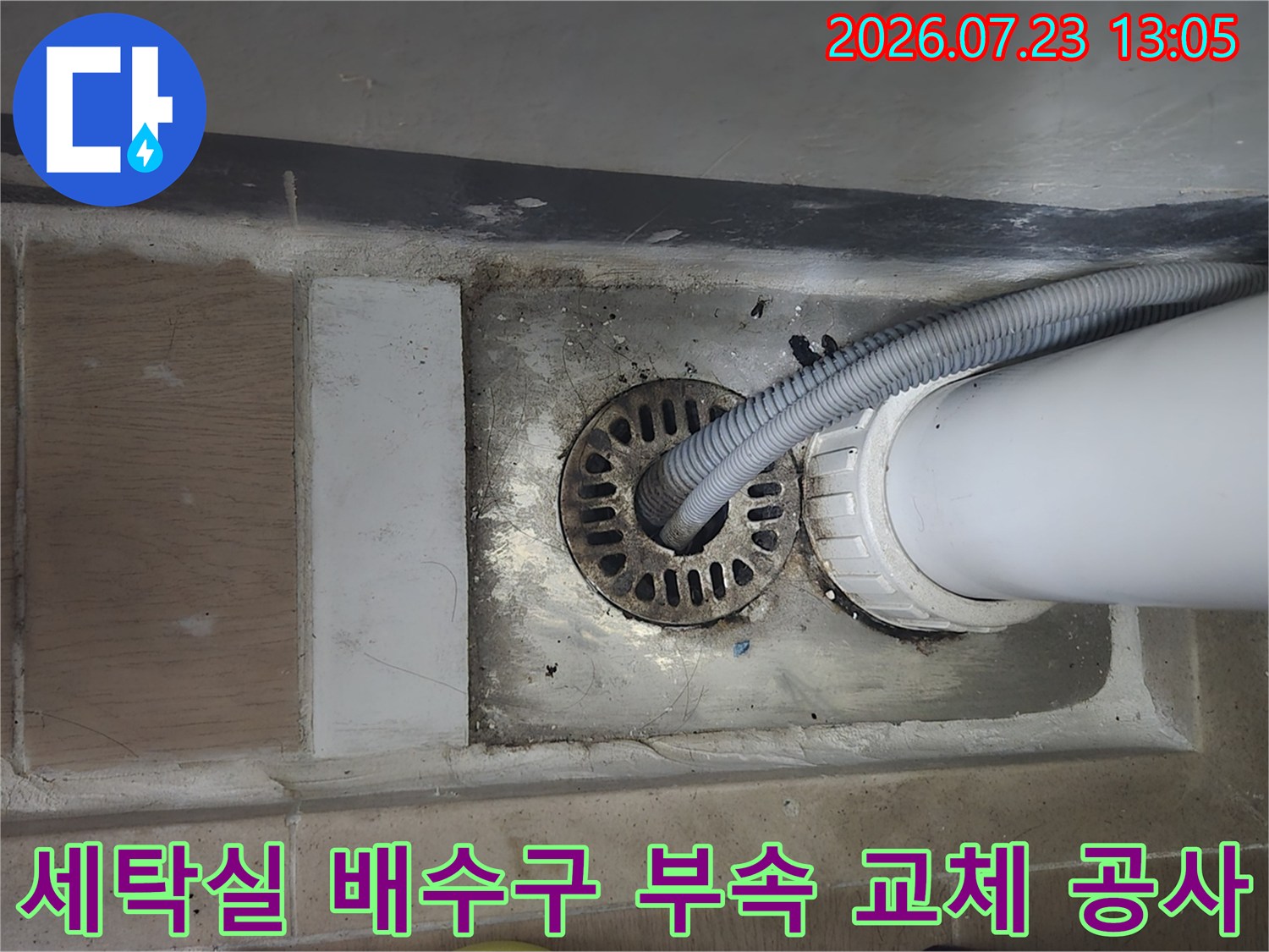 파손된 세탁실 배수 홈통과 연결된 관이 보이는 바닥 노출부