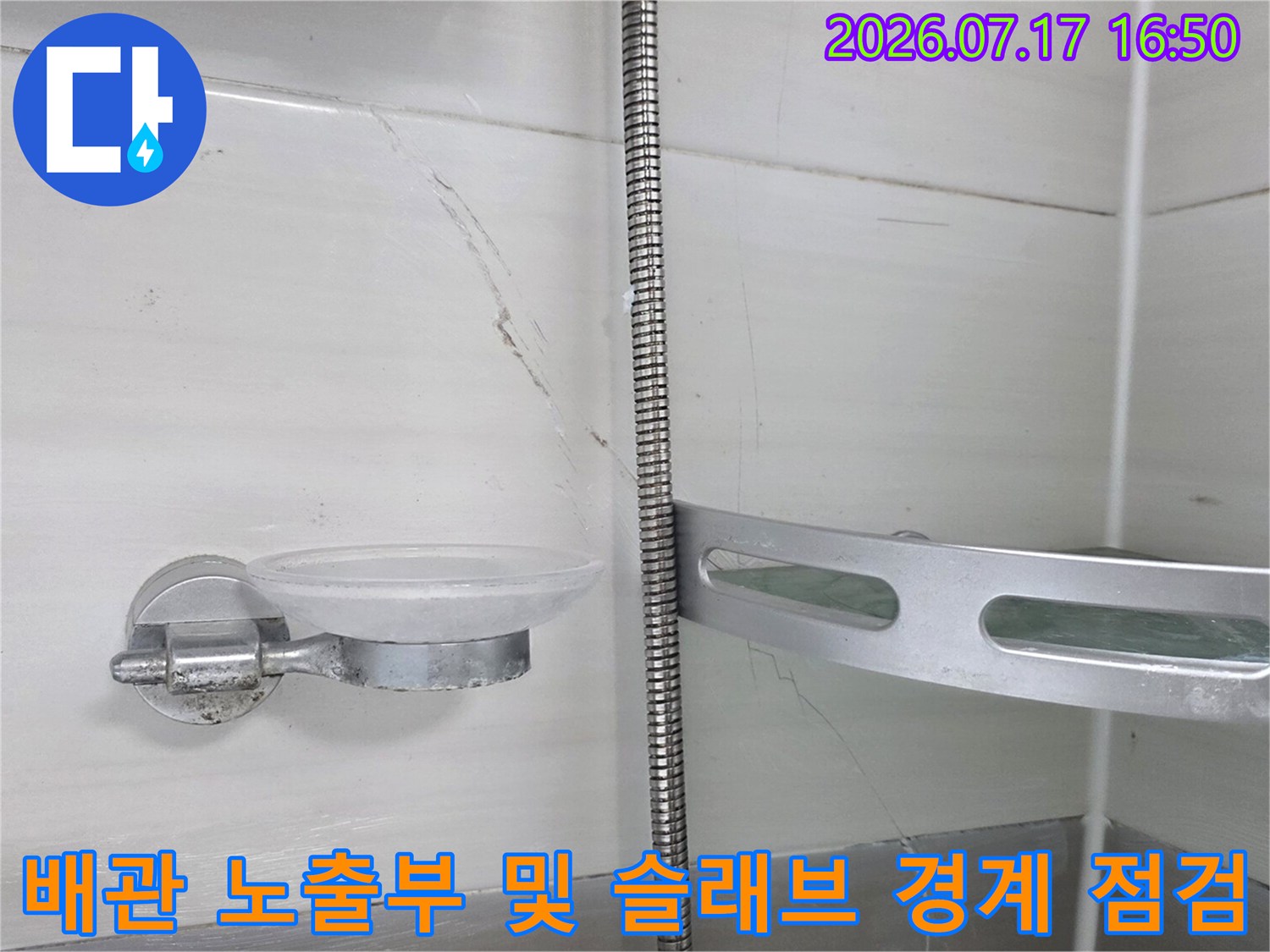 화장실 천장 속 노출된 금속 배관과 그 주변 콘크리트 구조를 조사하는 장면