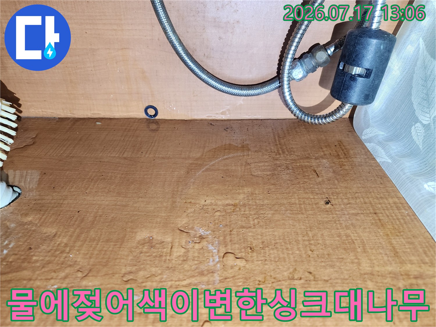 금속 배관과 연결된 싱크대 하부장 내부의 나무 판넬이 습기로 인해 갈색으로 변색된 모습