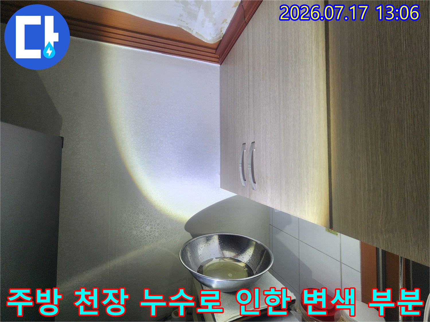 주방 상부장 위쪽의 하얀 천장에 발생한 노란색 누수 얼룩-사진