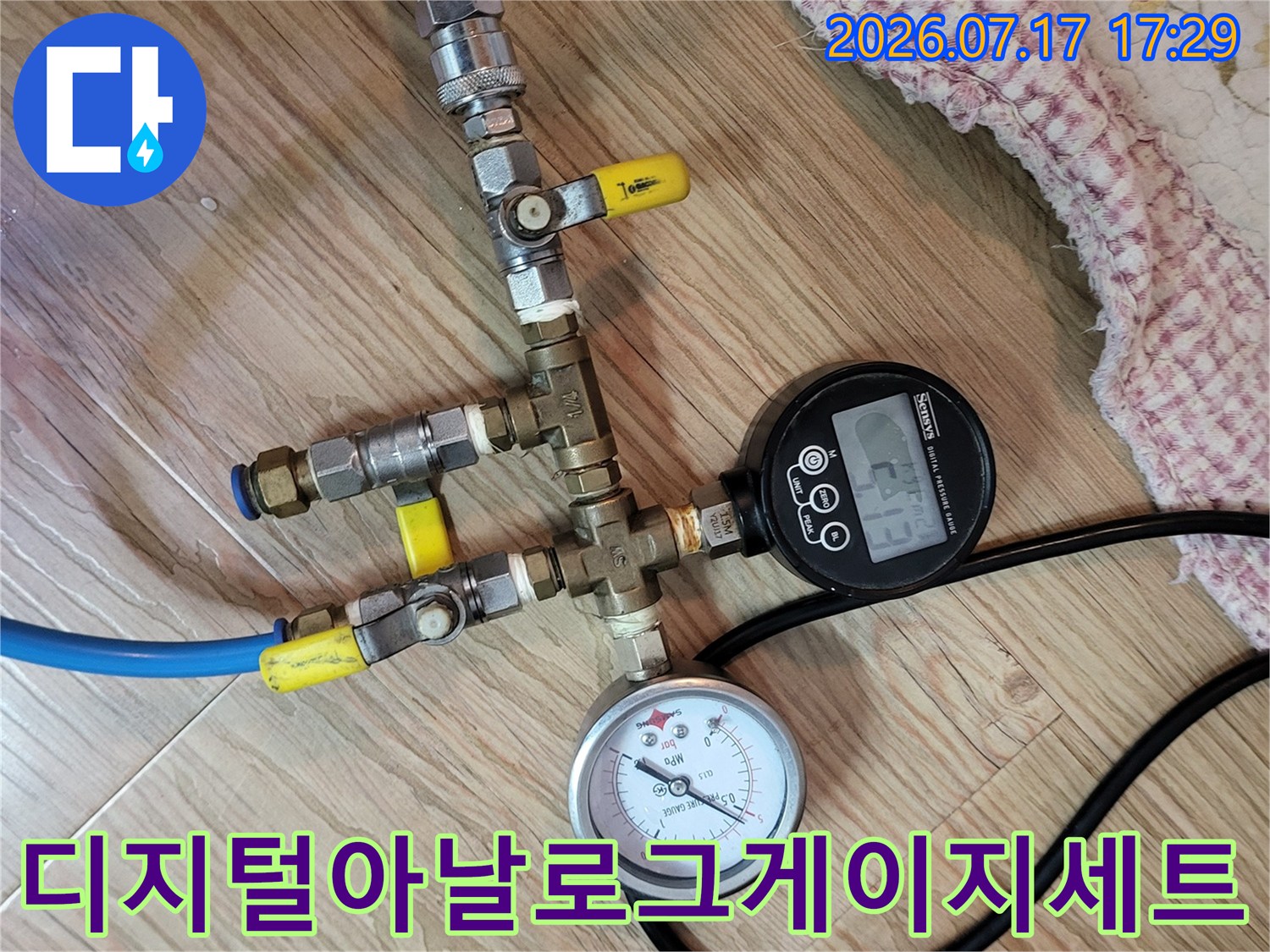 금속 밸브와 호스 그리고 두 개의 압력 측정기가 연결된 상태의 사진