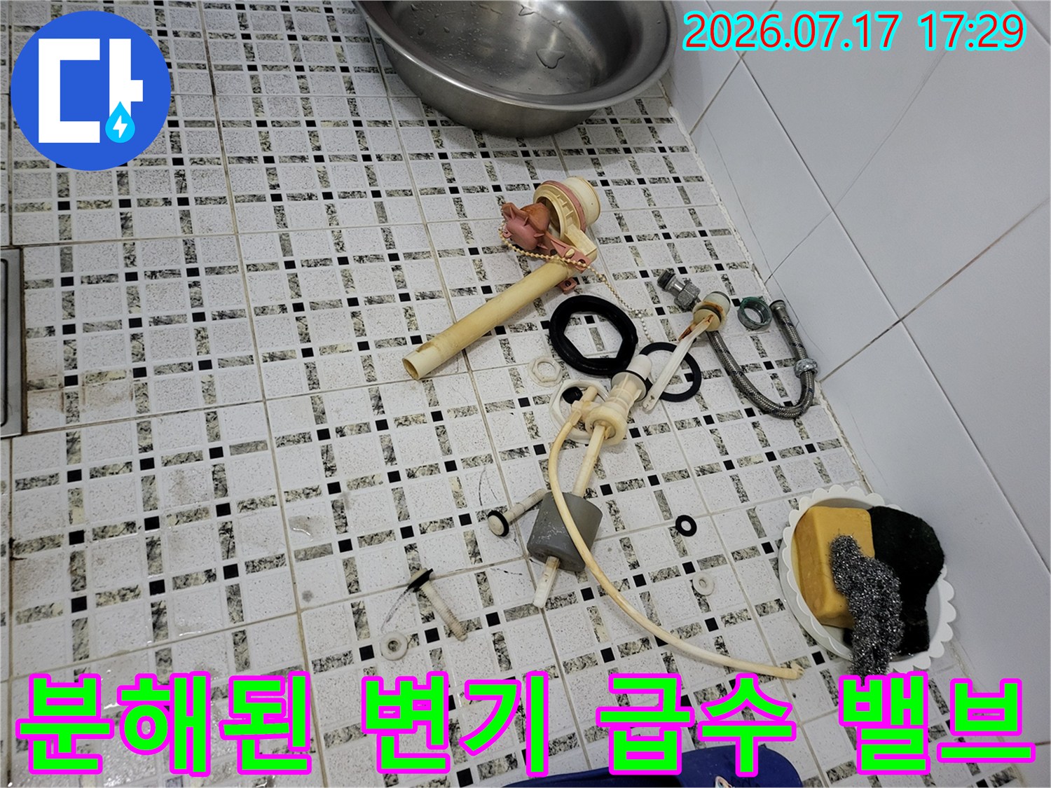 화장실 타일 바닥 위에-나열되어 있는 양변기 필밸브와 유연한 연결 호스 및 도구들