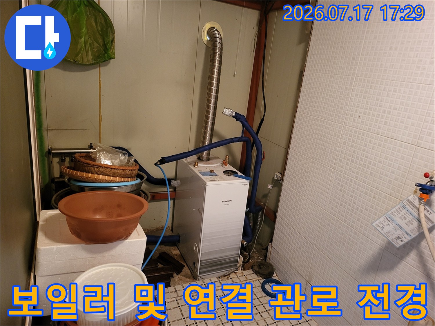 흰색 보일러-상단의 파란색 플라스틱 배관과 은색 자바라 호스가 설치된 모습