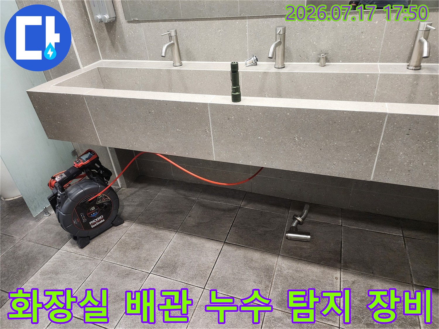 세면대 하단부의 금속 배수관과 그 옆에 놓인 전자기기 형태의 누수 탐지기