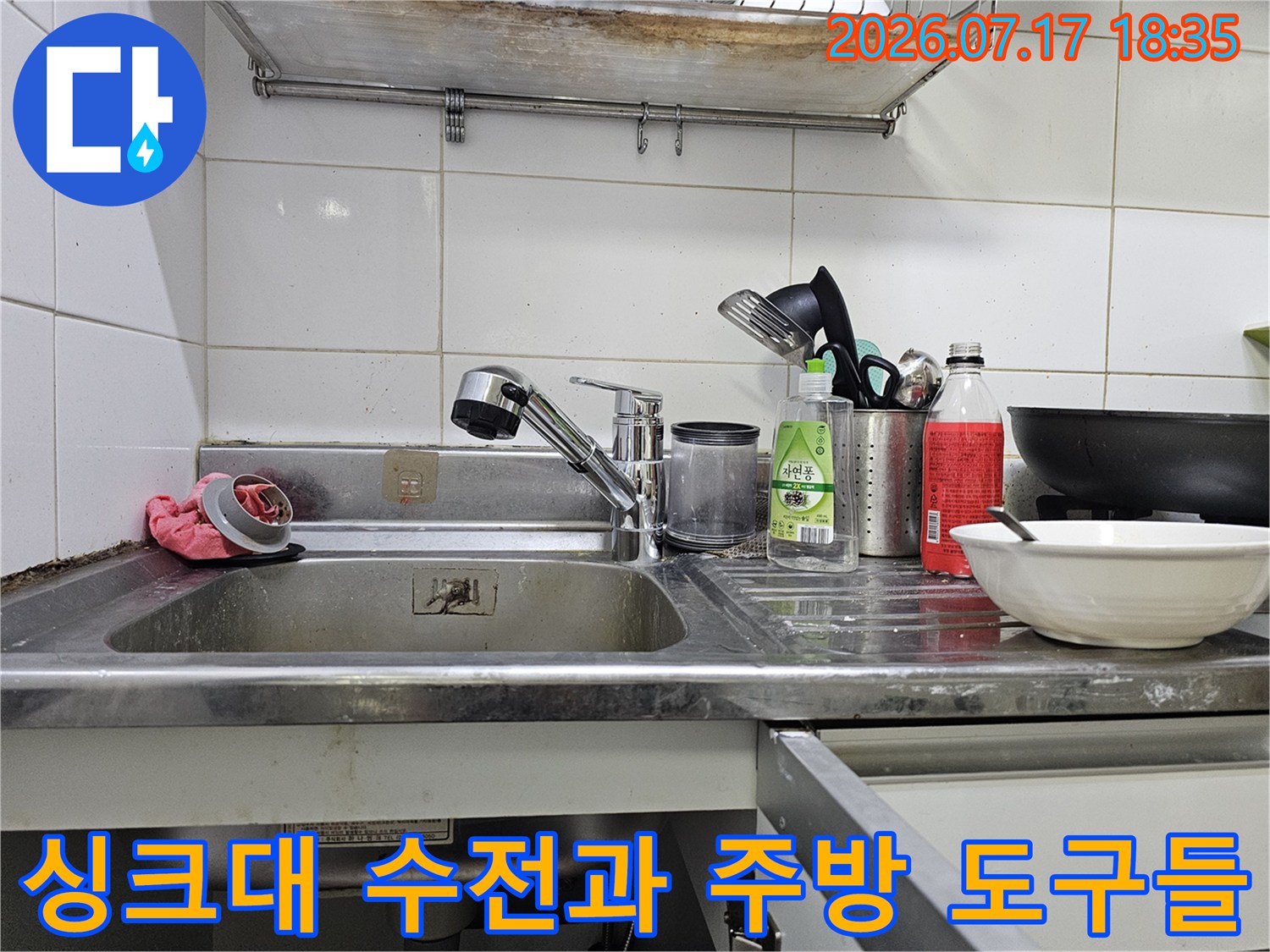 주방 싱크대 위에 놓인 세제통-그릇-수전이 보이는 정면 사진