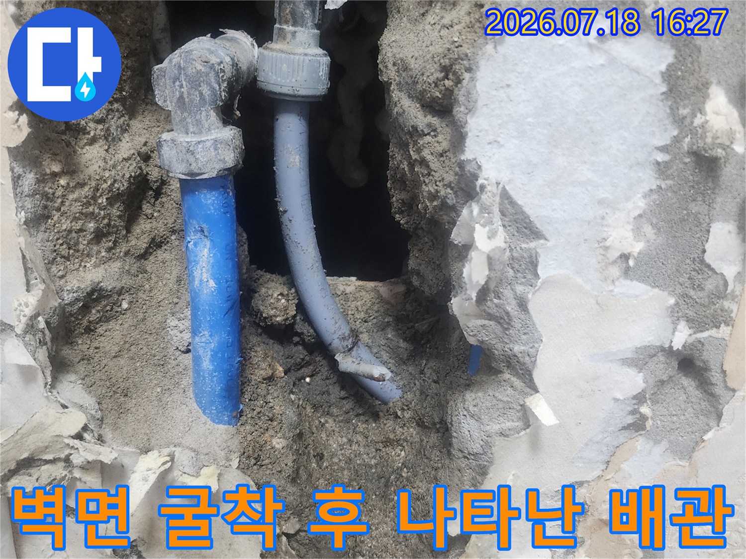 시멘트 잔해 속에 드러난 파란색 수도 배관과 엘보 부속의 모습