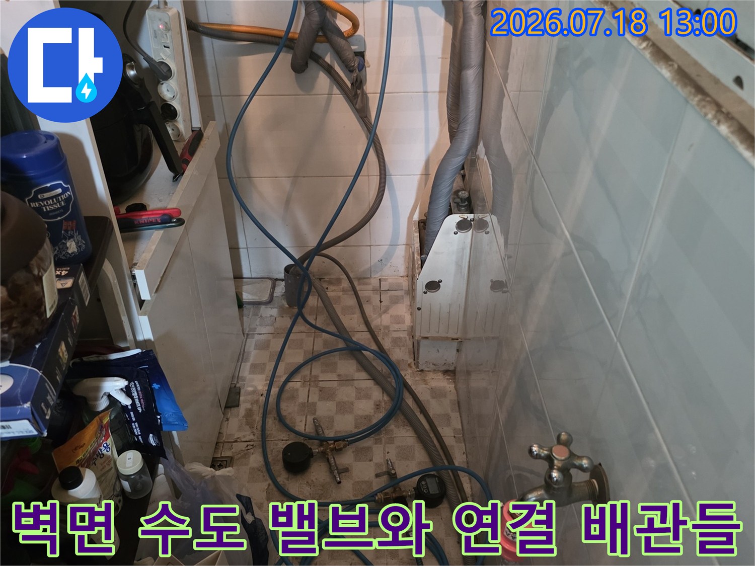 금속제 수도 밸브 두 개와 여기서 시작되는 파란색 수도 호스의 연결 모습
