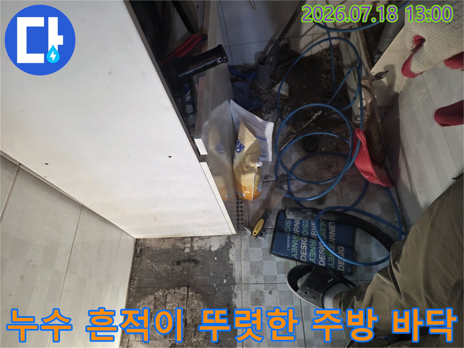 짙은 색으로 변한 타일과 그 위에 놓인 파란색 유연한 배관들