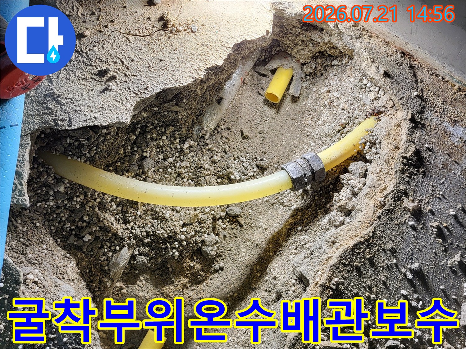 노란색 온수 배관이 드러난 굴착 부위의 수리 현장 사진