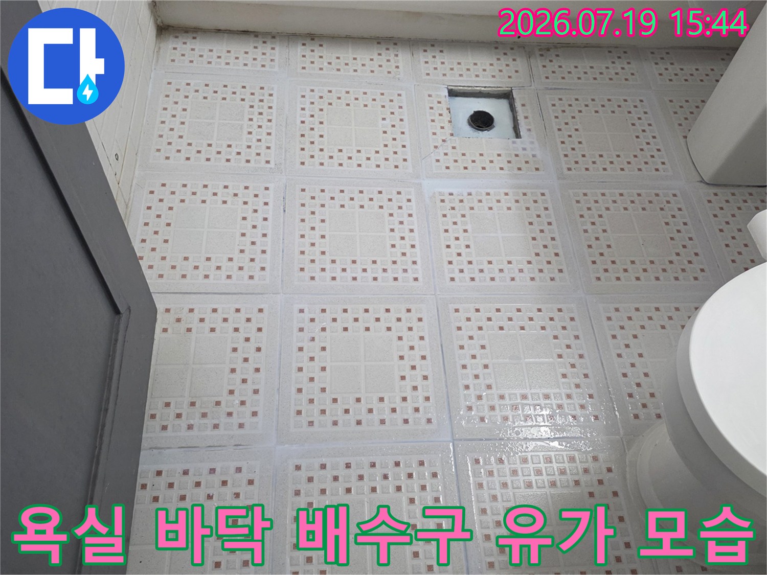 사각형 금속 재질의 욕실 하수구 덮개와 주변을 감싸고 있는 흰색 타일-바닥면