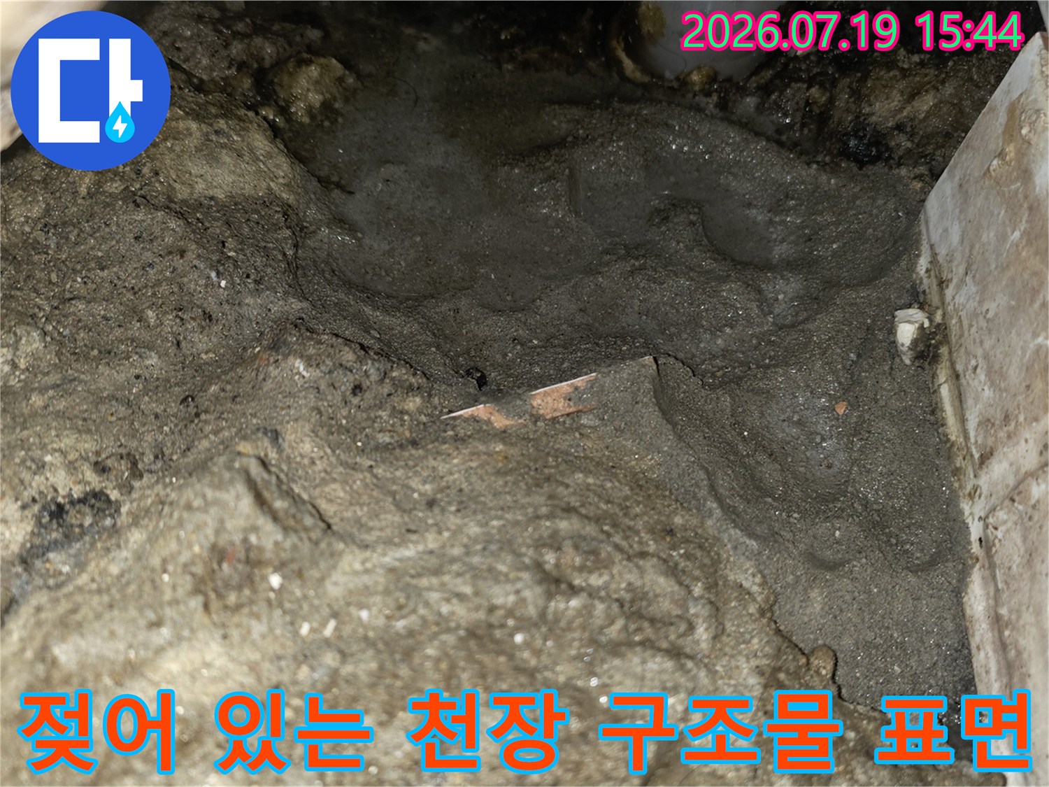 습기가 배어 나와 어둡게 변한 화장실 천장의 거친 콘크리트 슬라브 면