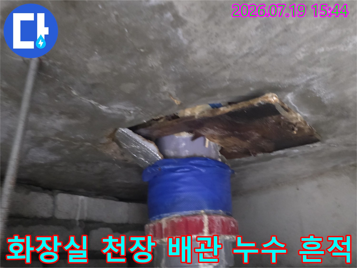 천장 콘크리트 슬래브-배관 주변의 젖은 얼룩과 파란색 보온재가 감싸진 배관 모습