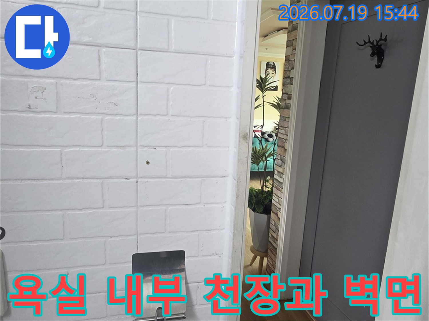 흰색 엠보싱 타일이 시공된 화장실 벽과 어두운 색상의 천장 전경