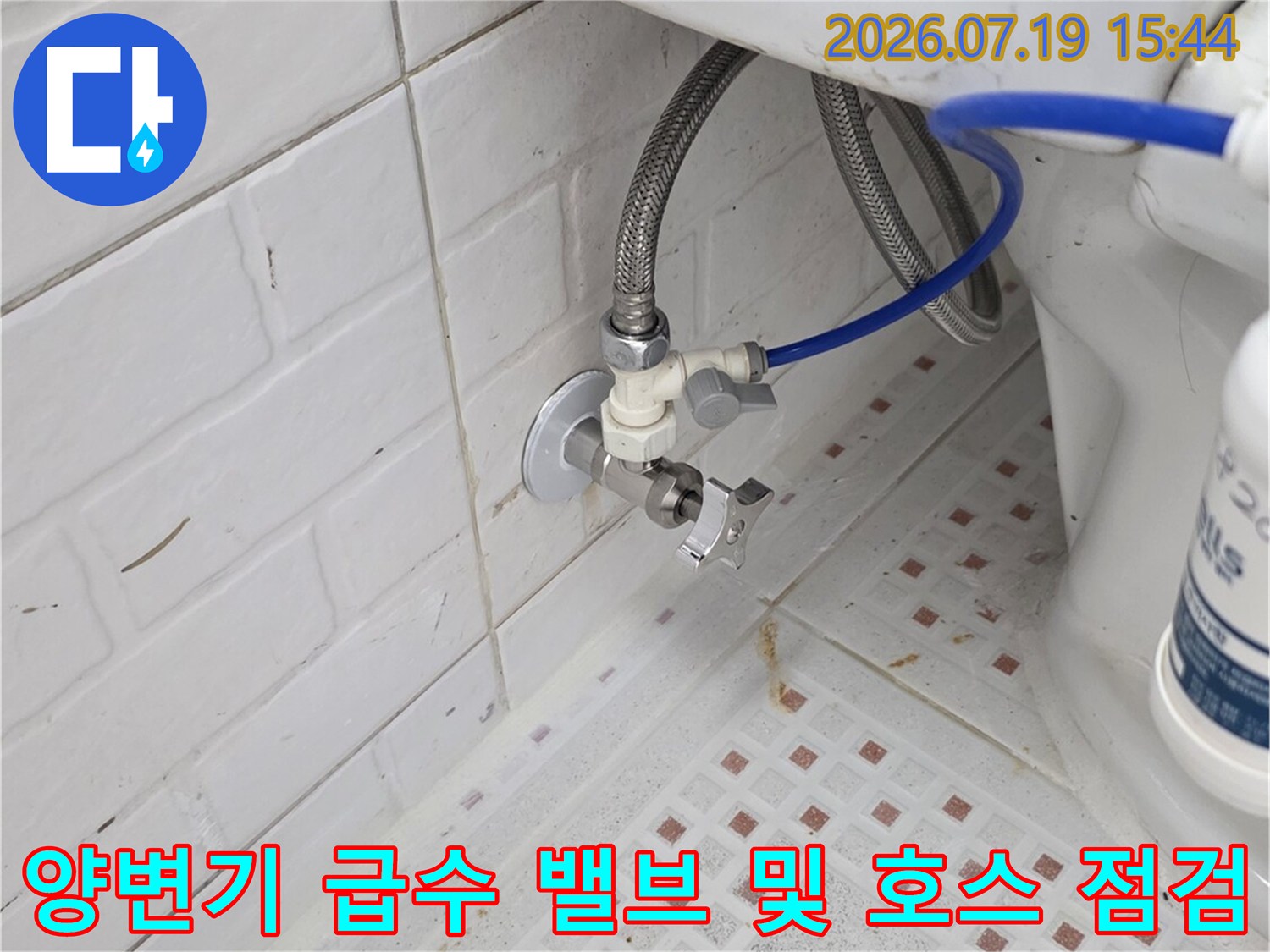 흰색 타일벽에 설치된 변기용 앵글밸브와 파란색 연결 호스-정밀 확인