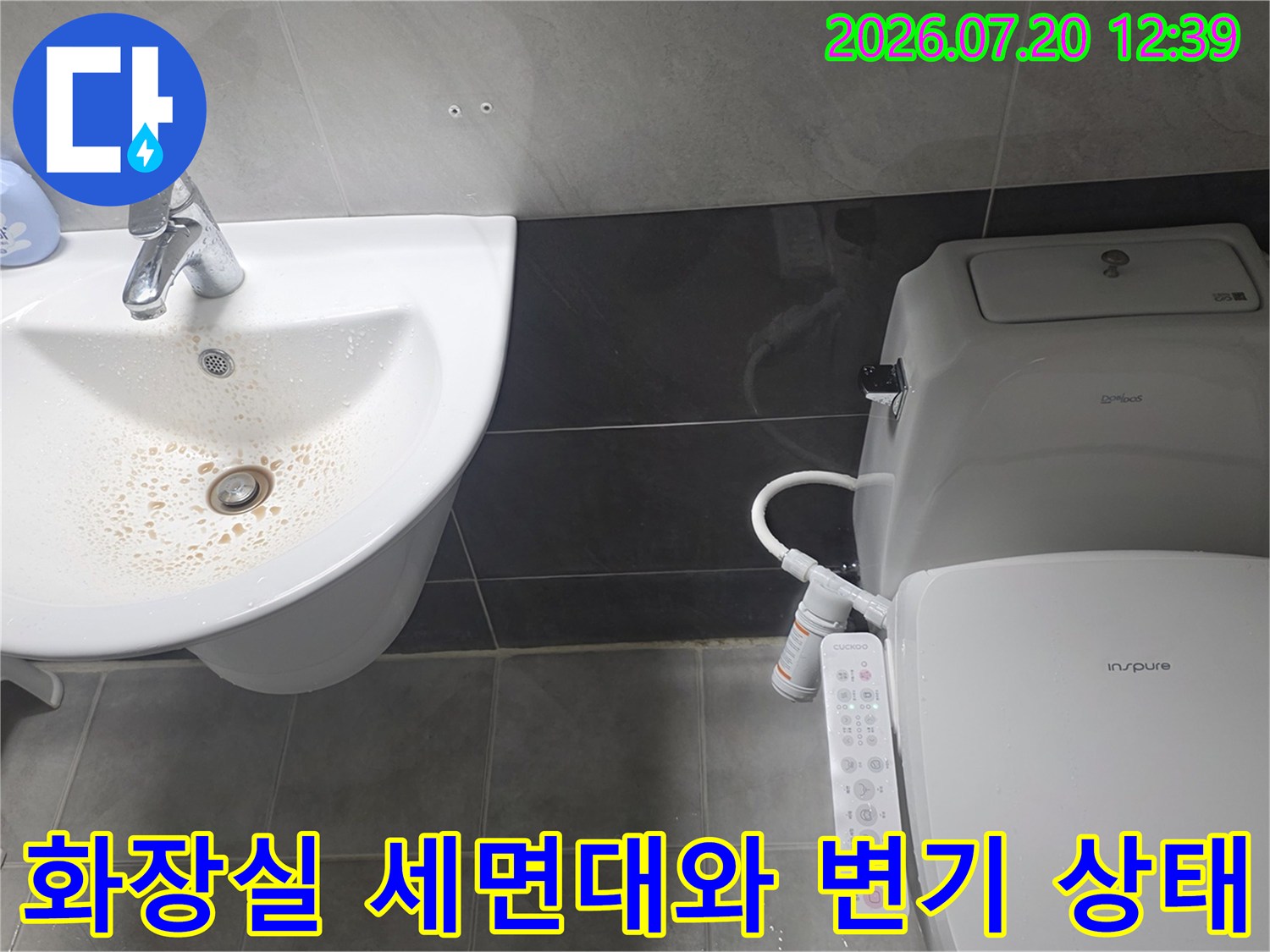 흰색 도기 세면대-배수구 주변의 갈색 오염물질-옆에 놓인 비데 일체형 변기
