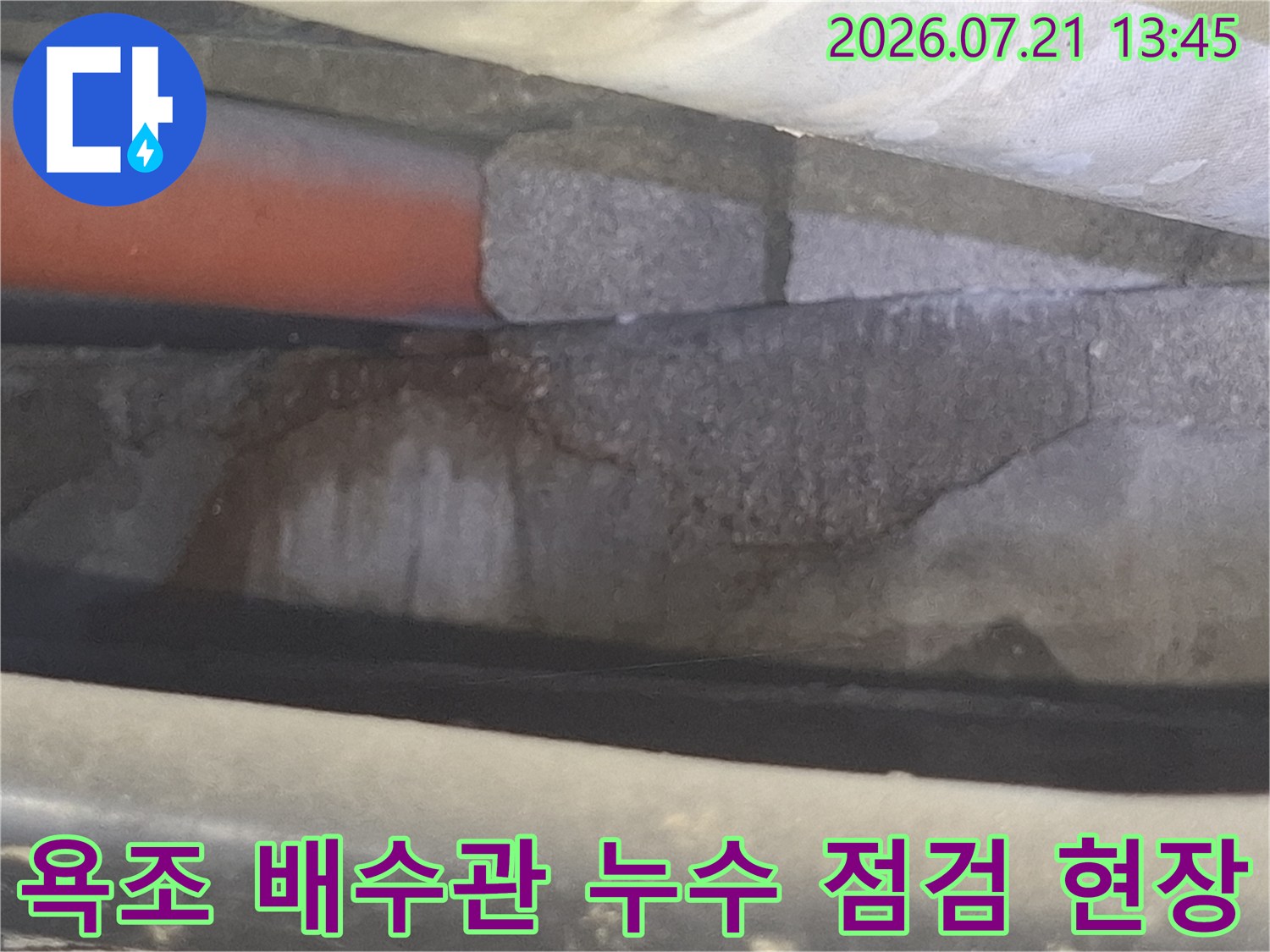 욕조 아래 노출된 배수 배관과 콘크리트 층의 누수 흔적을 확인하는 모습