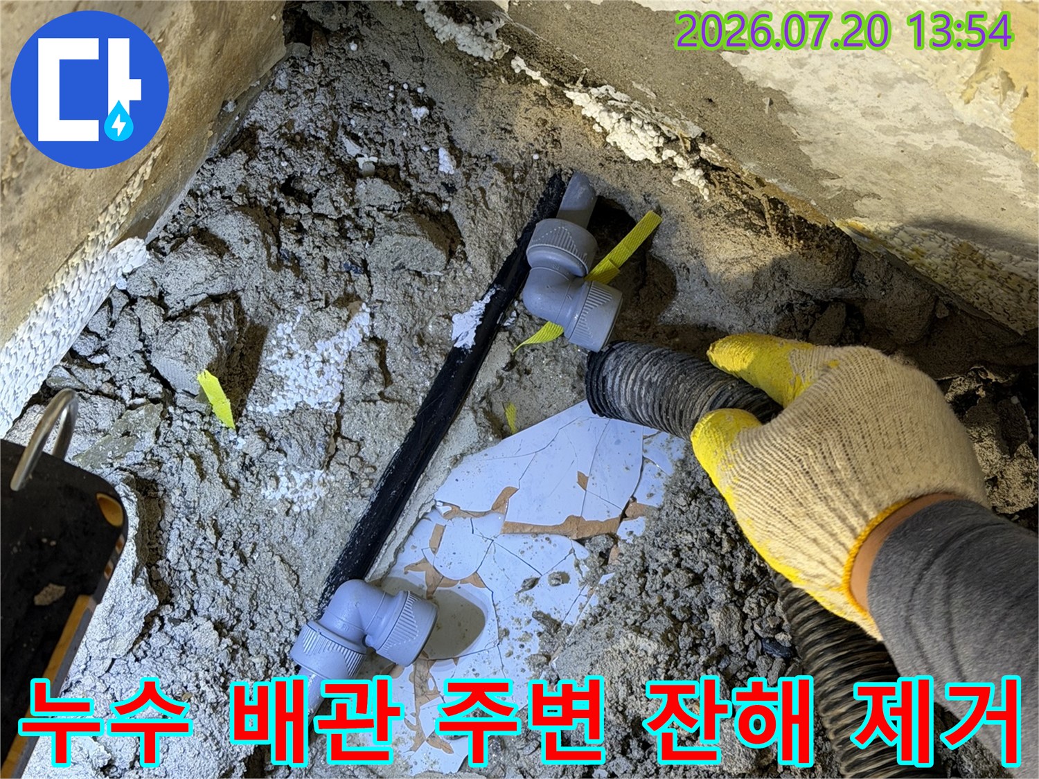 작업자가-집진기를-이용해-파손된-검정색-배관-주변의-흙을-치우는-사진