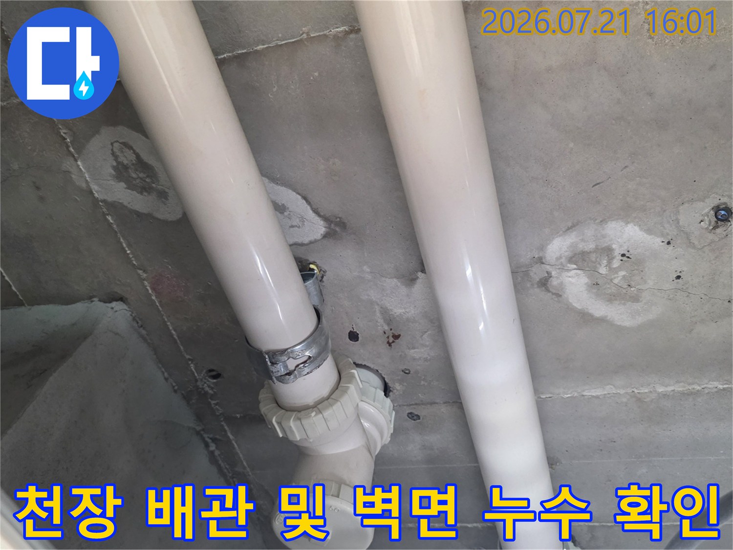 노출된 하얀색 배관과 그 주변에 형성된 습기 얼룩을 점검하는 모습
