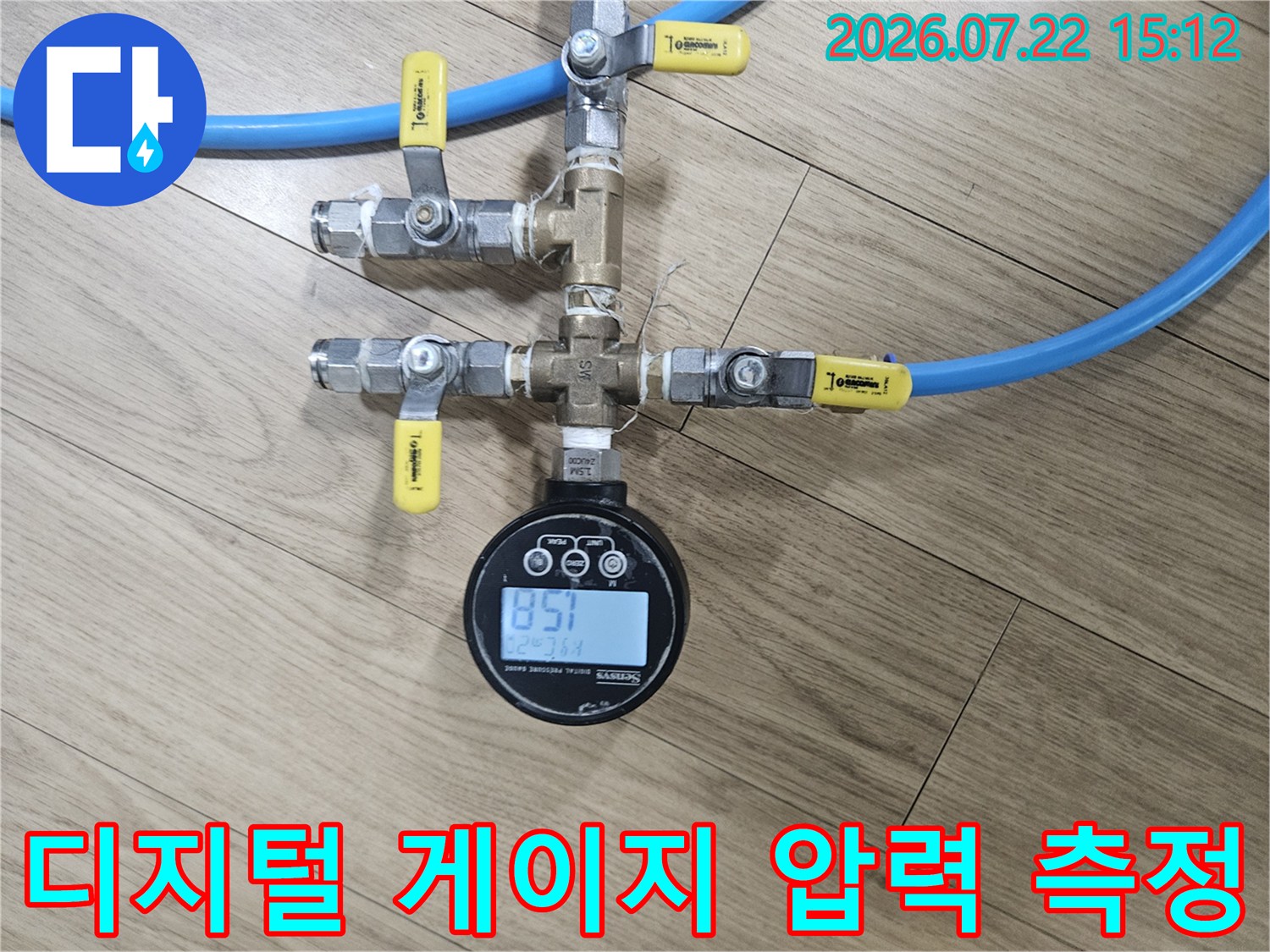 금속제 배관 분기점에 디지털 압력계와 파란색 호스가 연결되어 측정 중인 사진