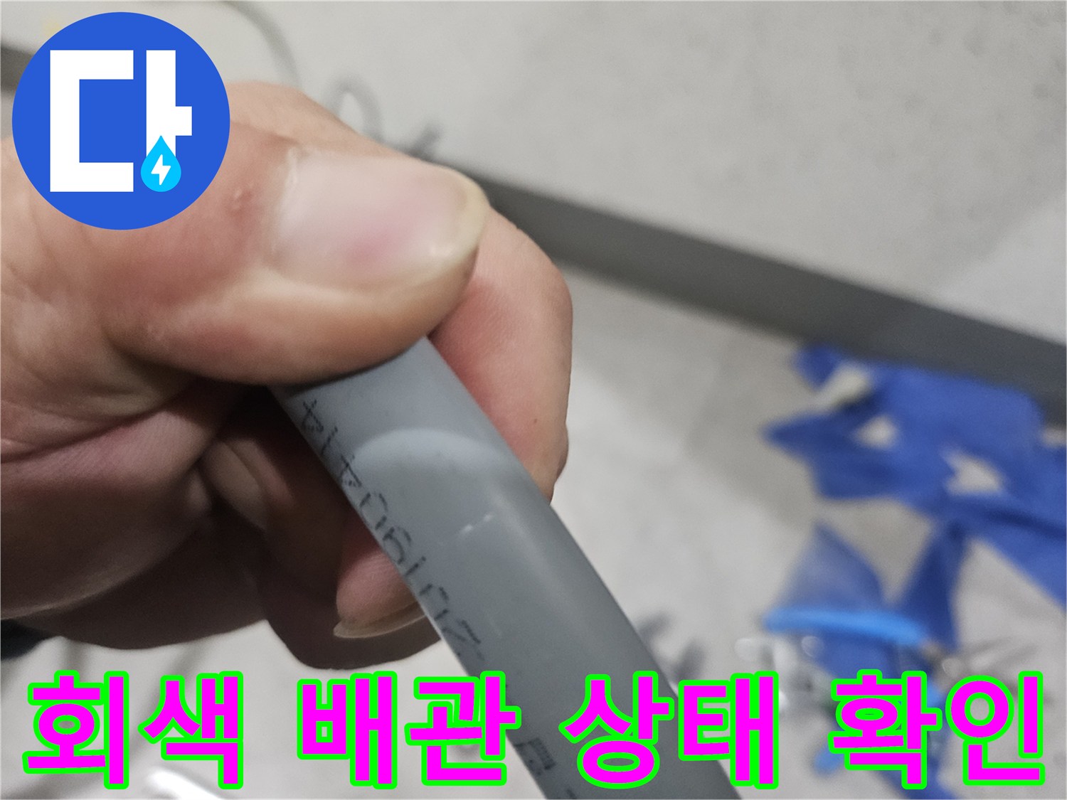 손으로 잡고 있는 회색 수도 배관의 표면 상태를 근접 촬영한 사진입니다.