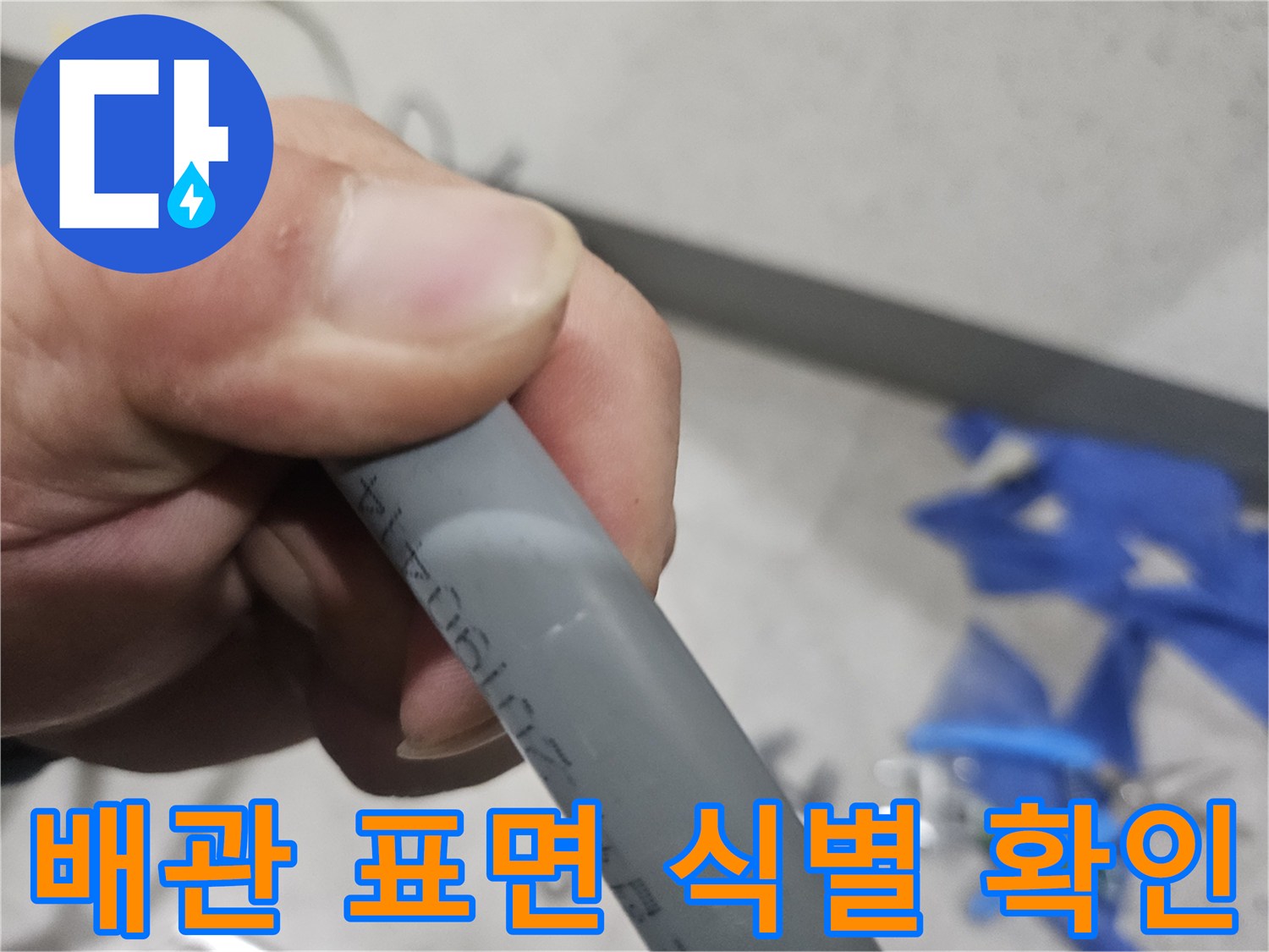 손으로 잡은 회색 배관에 적힌 숫자를 확인하는 사진입니다.