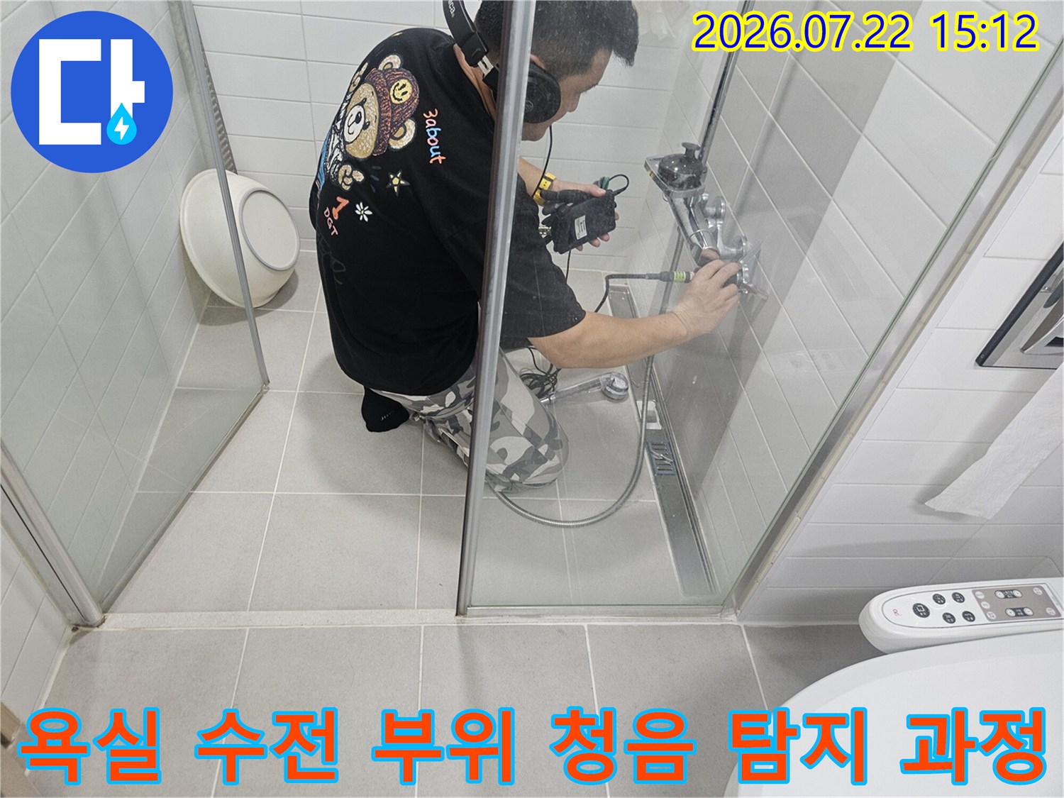 작업복을 입은 엔지니어가-화장실 샤워기 쪽에서-청음 장비를 사용하여 누수음을 측정하는 모습