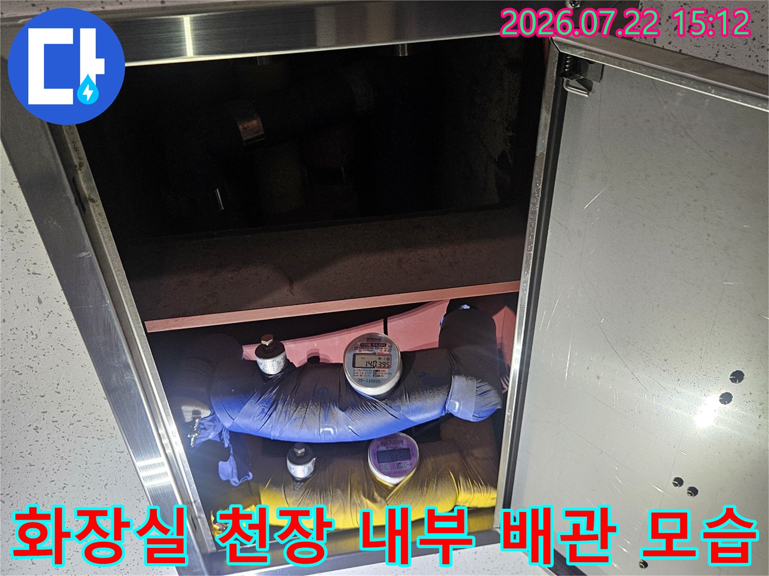 점검구 덮개를 열어 드러난 화장실 천장 속 보온재 처리된 파란색과 노란색 배관들