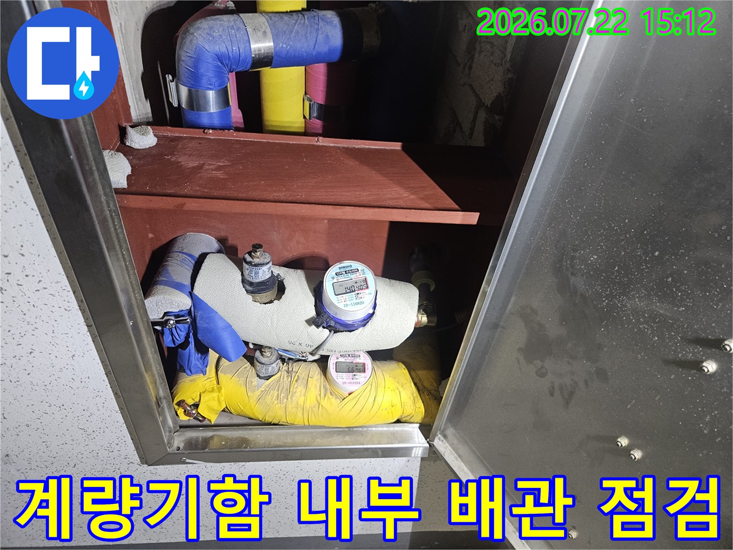 파란색과 노란색 보온재로 감싸진 배관과 디지털 계량기가 설치된 함 내부 모습