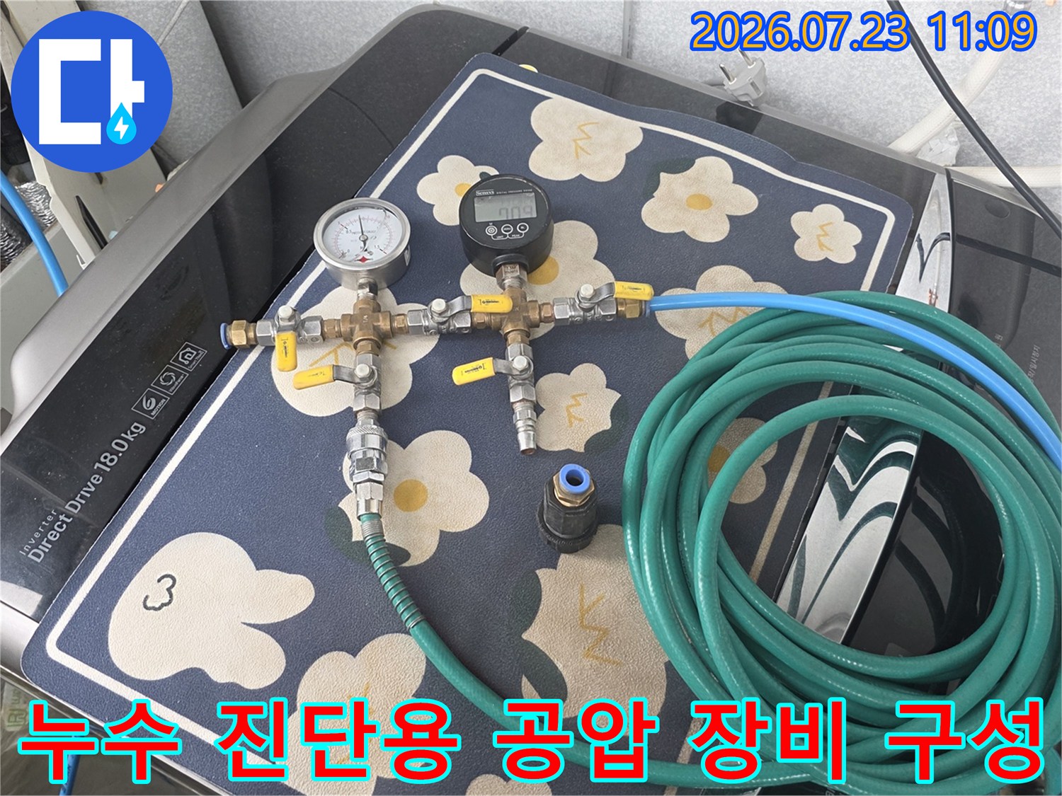 금속 밸브와 압력 게이지 그리고 녹색 호스가 연결된 배관 테스트 장비