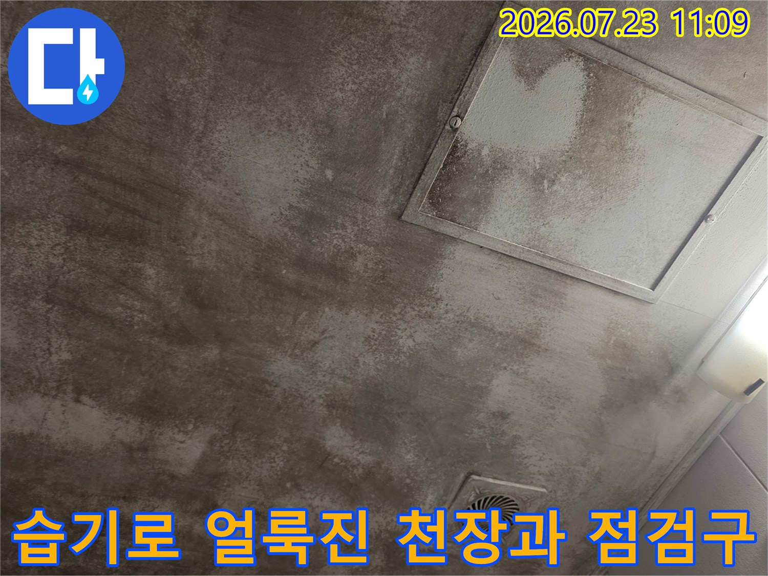 콘크리트 천장에 물자국과 곰팡이 흔적이 보이고 옆에 사각형 점검구가 설치된 모습