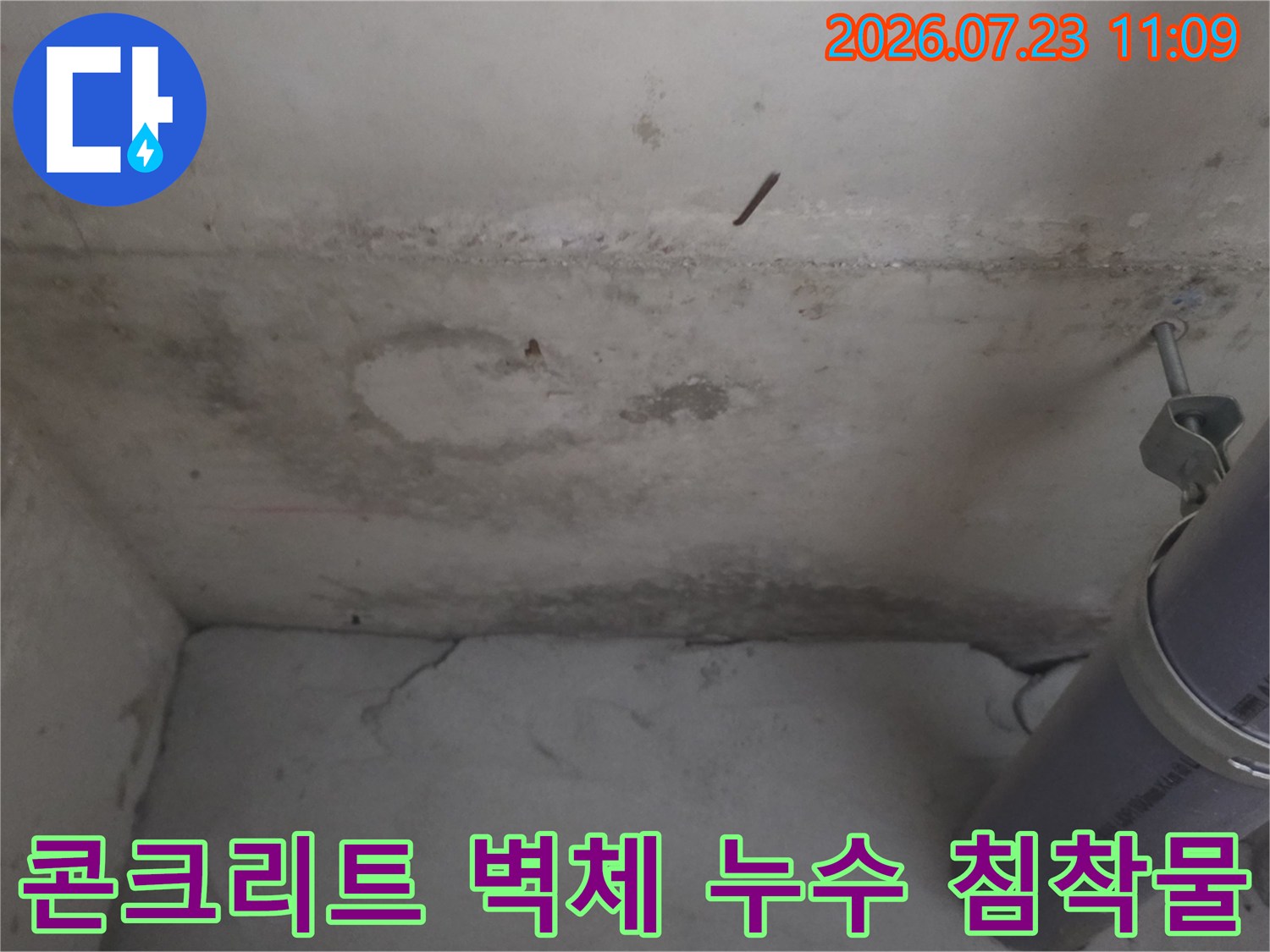 회색 배관과 그 뒤로 보이는 얼룩진 콘크리트 천장 내부 모습