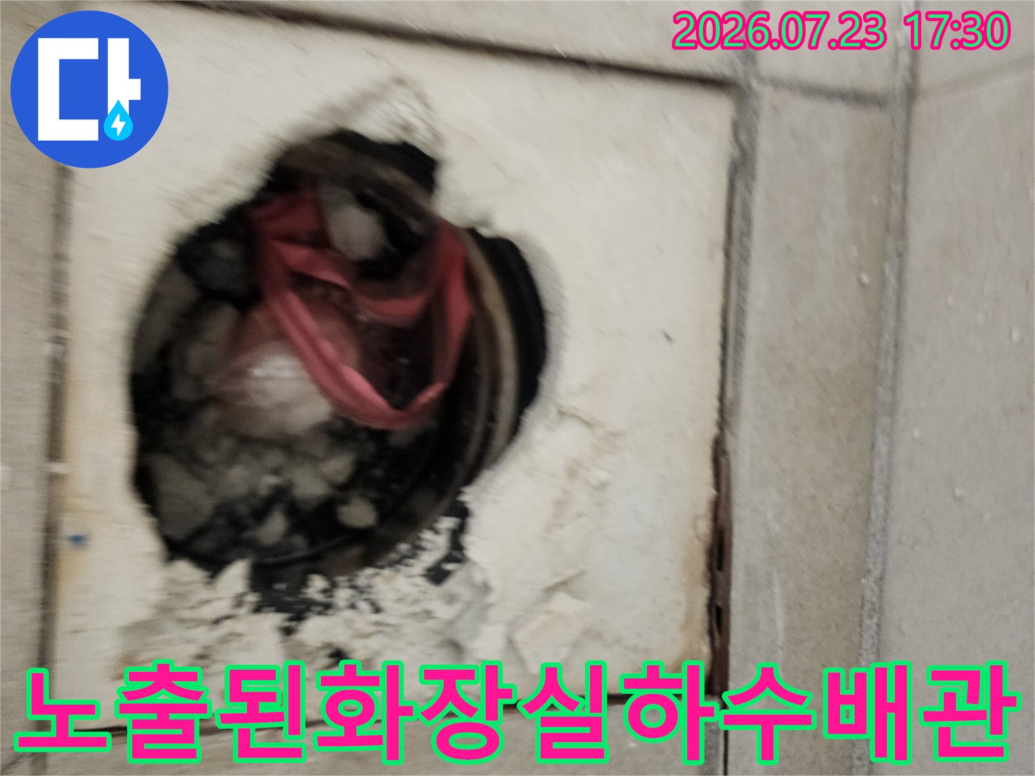 붉은색 배관이 노출된 화장실 바닥의 굴착 부위와 주변의 거친 마감 상태