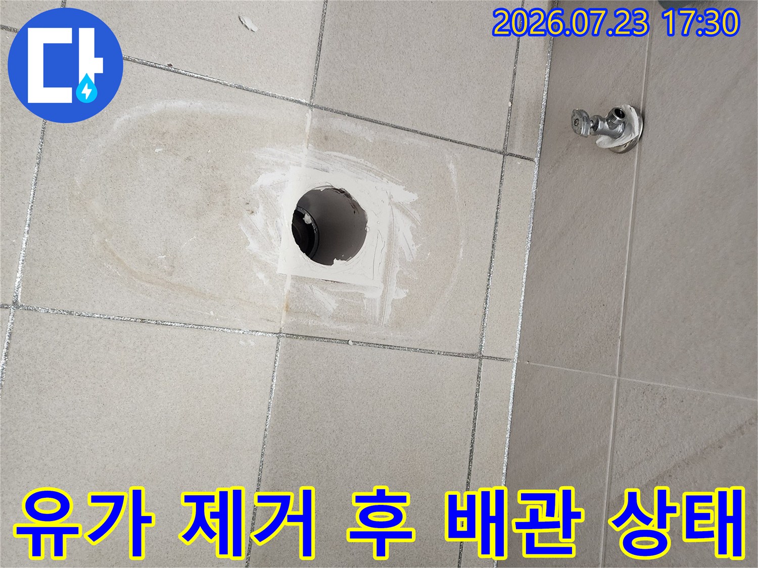 욕실 바닥 타일의 유가를 걷어내고 드러난 하수 배관과 주변 시멘트 부분