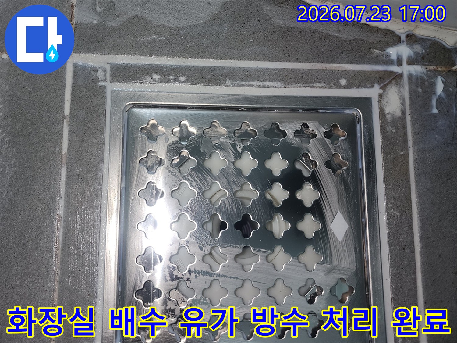 격자무늬의 스테인리스 배수구 덮개가 설치되어 있으며 테두리에 하얀색 방수제가 발라진 사진