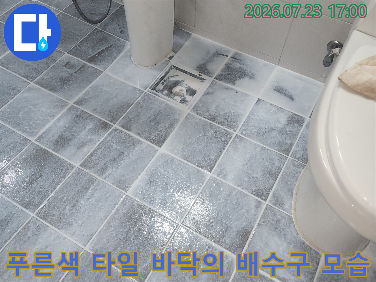 화장실 내부에 설치된 푸른색 타일과 배수 유가의 근접 사진